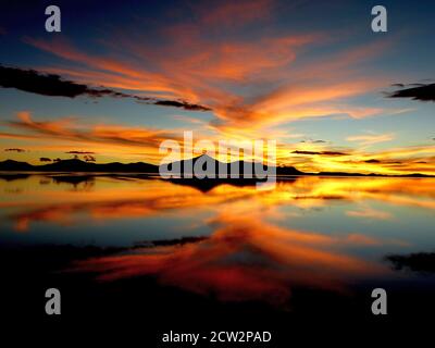 Spectaculaire coucher de soleil. Coucher de soleil orange doré. Réflexion magique de nuages dans le lac. Nature sauvage étonnante dans les appartements de sel d'Uyuni, Bolivie. Banque D'Images