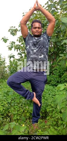 DISTRICT KATNI, INDE - 02 SEPTEMBRE 2019 : un homme de village indien faisant du yogasana sur fond de forêt de feuilles vertes. Banque D'Images