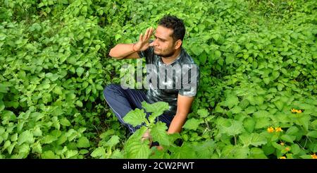 DISTRICT KATNI, INDE - 02 SEPTEMBRE 2019 : un garçon de village indien faisant du yogasana sur fond de forêt de feuilles vertes. Banque D'Images