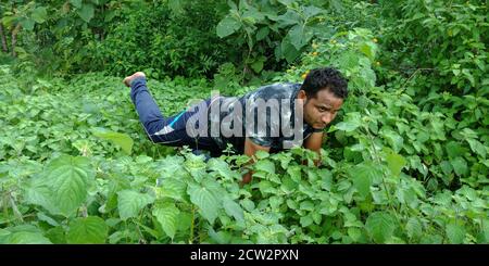 DISTRICT KATNI, INDE - 02 SEPTEMBRE 2019 : un garçon indien faisant du yoga pose le plus tard sur fond de forêt de feuilles vertes. Banque D'Images