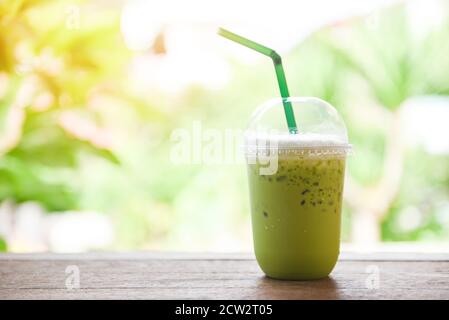 Smoothie au thé vert / thé vert Matcha avec du lait verre plastique sur la table en bois et fond vert nature Banque D'Images