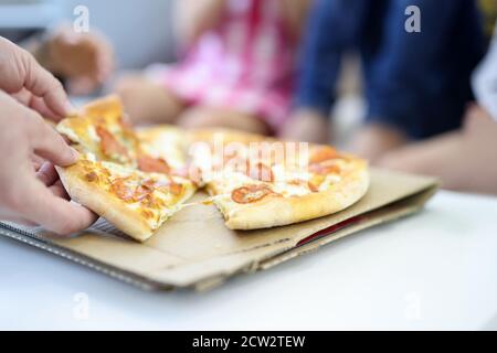 Sur la table se trouve la pizza, coupé en morceaux la main de l'homme tient deux piles Banque D'Images