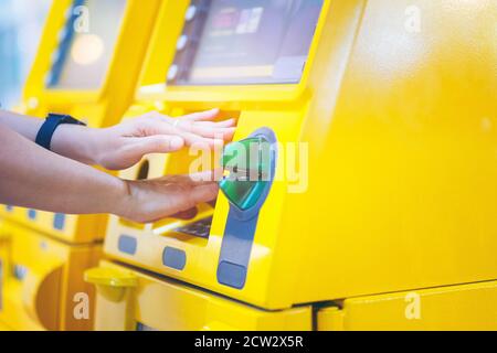 Une femme se couvrant les mains tout en entrant son code PIN à un ATM Banque D'Images