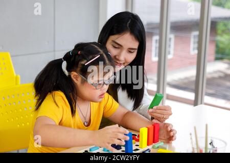 Asiatique fille avec le syndrome de Down jouer jouet puzzle avec son professeur en classe. Banque D'Images