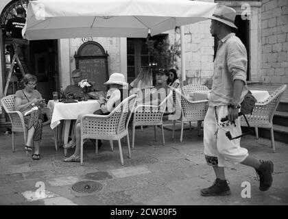 Kotor, Monténégro, 22 septembre 2019: Un homme assis dans un café regardant des montres exaspérées passant (B/W) Banque D'Images