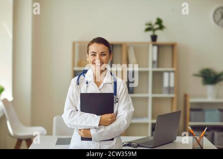 Femme médecin regardant l'appareil photo et souriant pendant la médecine en ligne consultation en clinique Banque D'Images