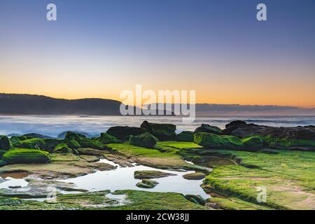 Paysage marin au lever du soleil avec de nouveaux rochers découverts et paysage changé de l'érosion de plage à Killcare Beach sur la côte centrale, Nouvelle-Galles du Sud, Australie. Banque D'Images