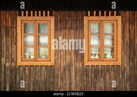 Un détail des planches sur la façade de la maison en bois avec une fenêtre. La couleur de la maison est ancienne et semble défraîchée. Banque D'Images