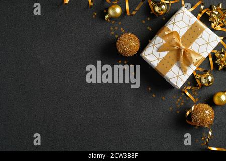 Composition de Noël pour les étals. Boîte cadeau de luxe, boules dorées et décorations sur fond noir. Vue de dessus avec espace de copie. Modèle de bannière Noël, Nouveau Banque D'Images