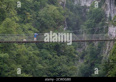 Senderistas con paraguas sobre la pasarela d’Holtzarte, gargantas de Holzarté, Larrau, región de Aquitania, departamento de Pirineos Atlánticos, Fran Banque D'Images