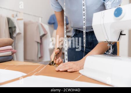 La couturière découpe le motif en ciseaux sur les lignes d'esquisse pour la machine à coudre. Lieu de travail de couturière Banque D'Images