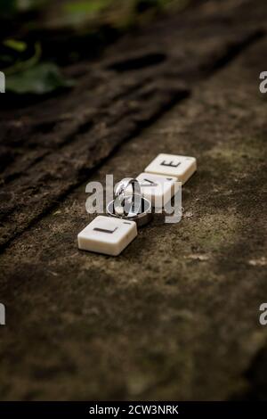 Des tuiles avec des lettres orthographiant le mot « Love » avec des anneaux de mariage photographiés sur le côté Banque D'Images