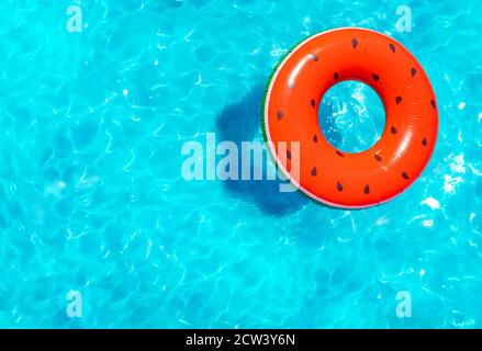 Melon d'eau gonflable rouge avec bouée de graines nager dans la natation vue sur la piscine depuis le dessus Banque D'Images