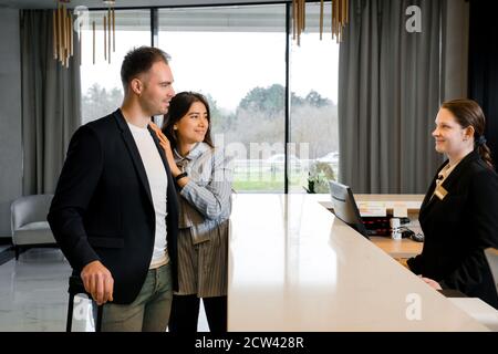 Couple et réceptionniste au comptoir de l'hôtel. Un jeune couple s'est fait enregistrer à l'hôtel Banque D'Images