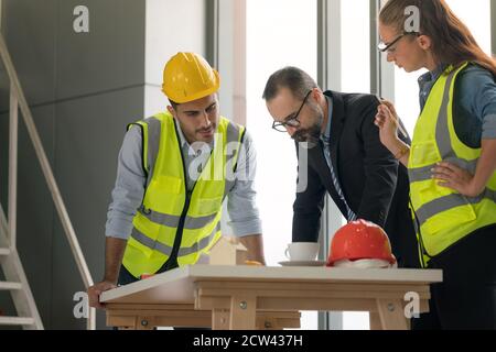 Équipe d'architectes multiethniques travaillant sur les plans de construction dans la salle de réunion. Les ingénieurs discutent du projet au bureau. Banque D'Images