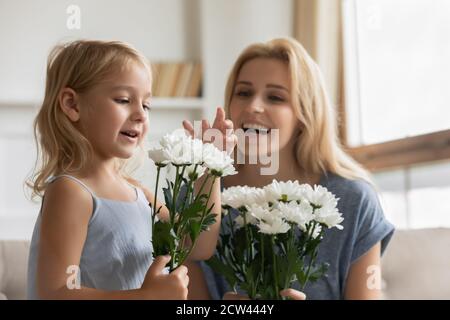 Des sœurs plus jeunes et plus âgées enchantés recevant des fleurs le 8 mars Banque D'Images