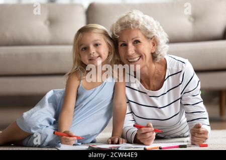 Grand-mère senior et petite fille dessin des images sur le sol chauffé Banque D'Images