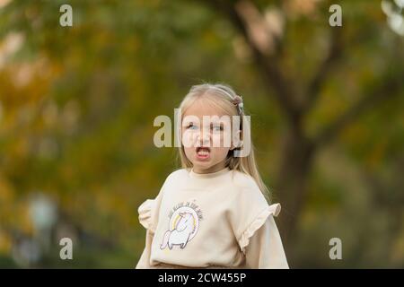 Jolie petite fille élégante avec de longs cheveux blonds marchant dans le parc d'automne. Mode automne pour enfants. Bonne enfance. Portrait de style de vie. Enfant caucasien 6 Banque D'Images