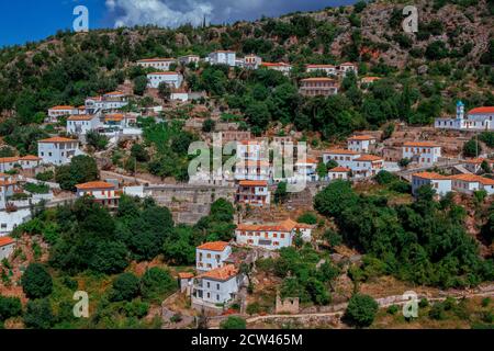 Vue sur le village albanais - maisons blanches traditionnelles avec toits d'orange et volets en bois sur les fenêtres - sur la colline de montagne, petite église et route. Banque D'Images