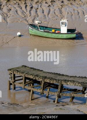 Bateau de pêche vert pois amarré sur les rives boueuses de La rivière Ax près de Weston super Mare dans Somerset Royaume-Uni Banque D'Images