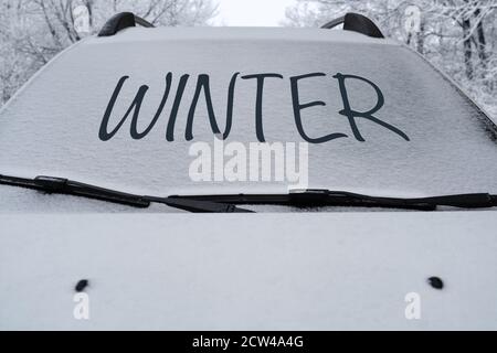 Voiture garée avec de la neige sur le pare-brise et l'inscription Hiver Banque D'Images