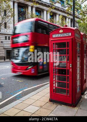 Emblématique Londres - un bus rouge passe devant deux téléphones rouges traditionnels dans le centre de Londres. Mouvement flou du mouvement du bus. Tourisme de Londres. Banque D'Images