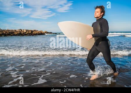 Portrait d'un jeune surfeur laissant l'eau avec planche de surf sous son bras. Sport et sport nautique. Banque D'Images