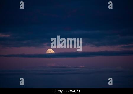La lune se lève derrière les nuages la nuit Banque D'Images