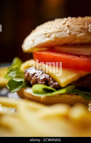 cheeseburger entouré de frites sur une table noire Banque D'Images