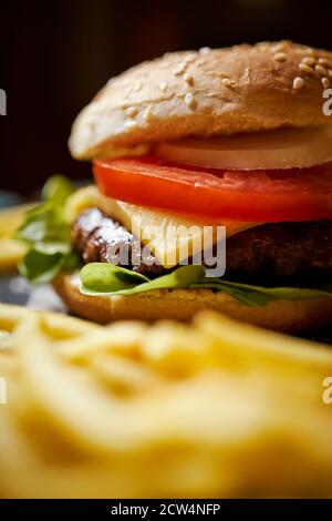 cheeseburger entouré de frites sur une table noire Banque D'Images