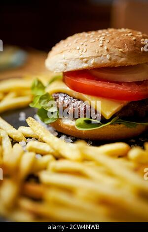 cheeseburger entouré de frites sur une table noire Banque D'Images