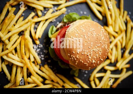 cheeseburger entouré de frites sur une table noire Banque D'Images