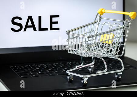 panier sur le clavier de l'ordinateur portable. Écran de surveillance avec le mot VENTE. Le concept des achats et des ventes en ligne dans les magasins en ligne Banque D'Images