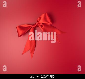 Grand noeud rouge sur fond rouge. Banque D'Images