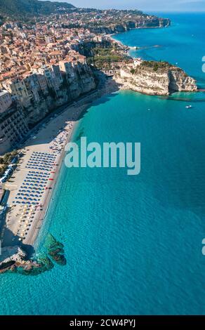 Vue aérienne sur une plage avec parasols et baignoires. Maisons sur le rocher. Promontoire du Sanctuaire de Santa Maria dell'Isola, Tropea, Calabre, Italie Banque D'Images