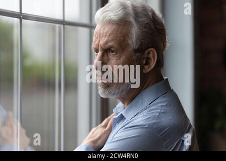 Un homme âgé malheureux regarde dans la réflexion de distance Banque D'Images
