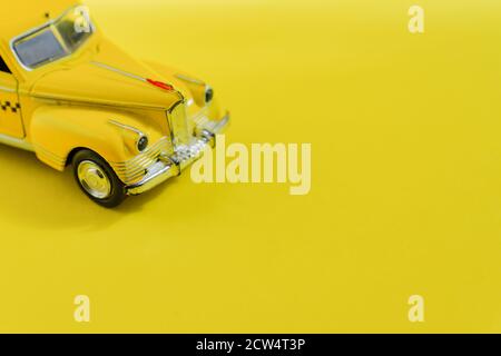 Vieille voiture-taxi rétro jaune jouet sur fond jaune avec espace de copie. Mise au point sélective, Travel concept Banque D'Images