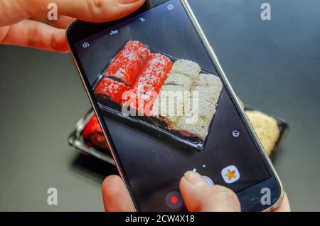 Une fille photographie des sushis rouges et blancs au téléphone sous différents angles. Photo gros plan. Banque D'Images