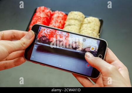 Une fille photographie des sushis rouges et blancs au téléphone sous différents angles. Photo gros plan. Banque D'Images