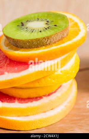 pile de tranches d'oranges, de citrons, de kiwi, de pamplemousse sur fond de bois Banque D'Images
