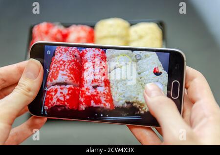 Une fille photographie des sushis rouges et blancs au téléphone sous différents angles. Photo gros plan. Banque D'Images