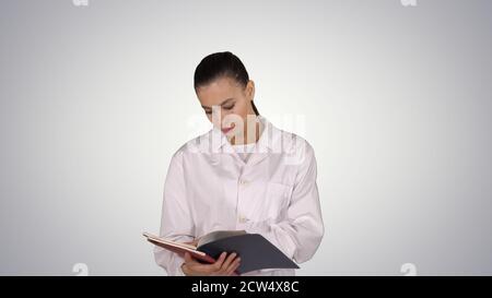 Jeune médecin femme lisant la documentation tout en marchant sur le gradient Banque D'Images