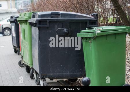 Une rangée de poubelles vertes et noires le long de la rue. Banque D'Images