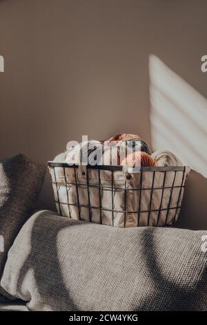 Panier de skeins de couleur terre de fil à l'intérieur d'un appartement, lumière du soleil de la fenêtre dessus, foyer sélectif. Banque D'Images