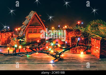 Maison de jouets sur fond de bois guirlande de Noël entinée, il y a de petits cadeaux et des branches de l'arbre de Noël. Magnifique arrière-plan de Noël. Banque D'Images