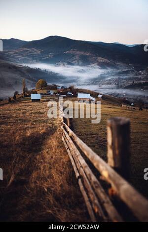 Paysage rural d'automne, en avant-plan clôture, arrière-plan foggy montagnes.Romania,Bucovina Banque D'Images