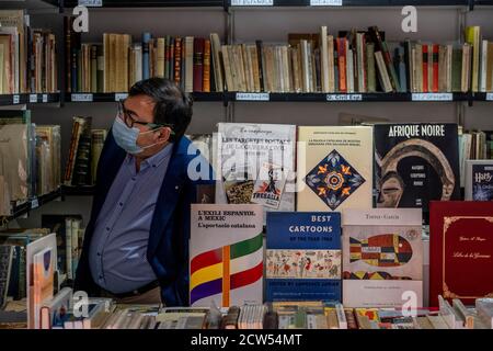 Un visiteur portant un masque facial comme mesure préventive cherche des livres utilisés.sous l'impact de la pandémie de Covid19, Barcelone célèbre sa 69e occasion de livre Foire, ancien et nouveau, dans l'enclave habituelle de Passeig de Gràcia mais avec des mesures anti-contagion. Banque D'Images