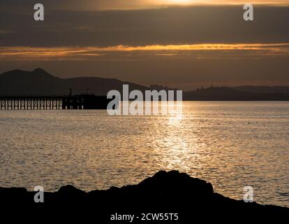 East Lothian, Écosse, Royaume-Uni, 27 septembre 2020. Météo au Royaume-Uni : coucher de soleil sur le Firth of Forth en regardant vers la ligne d'horizon caractéristique d'Édimbourg avec une silhouette de Cockenzie jetée désutilisée Banque D'Images