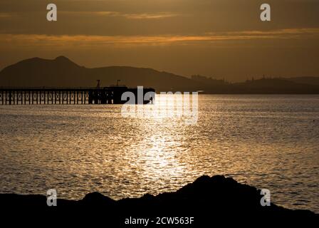 East Lothian, Écosse, Royaume-Uni, 27 septembre 2020. Météo au Royaume-Uni : coucher de soleil sur le Firth of Forth en regardant vers la ligne d'horizon caractéristique d'Édimbourg avec une silhouette de Cockenzie jetée désutilisée Banque D'Images
