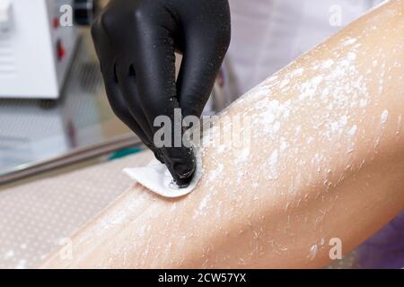 Une esthéticienne se prépare à cirer les jambes des femmes dans le centre de spa. Préparation pour l'épilation, en mettant un peu de poudre blanche Banque D'Images